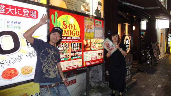 employees wave in front of the restaurant sign